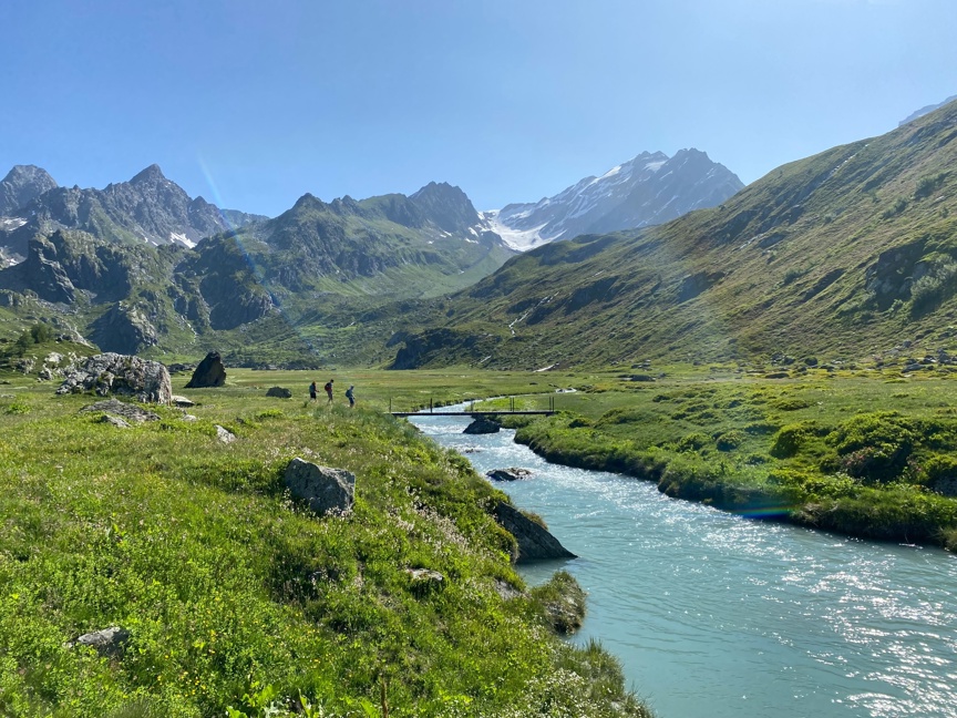 Hiking over a stream in the French Alps in summer.